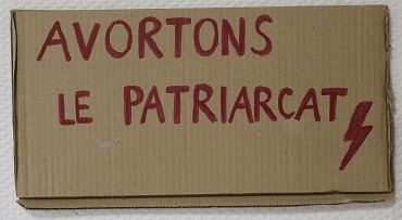 Pancarte de manifestation en carton avec le slogan avortons le patriarcat inscrit dessus